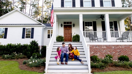 A family sits outside their home. - Fox Business News