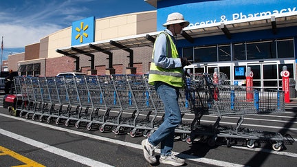 A Walmart employee pushes a line of shopping carts across the pedestrian crosswalk outside the Grocery & Pharmacy entrance canopy of a Walmart retail store in Heber City, Utah, United States, on October 2, 2026. - Fox Business News