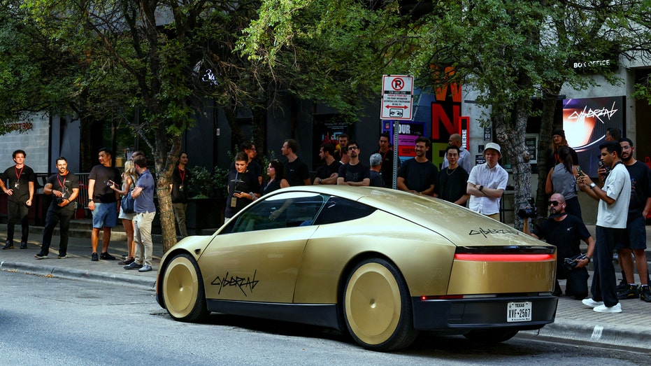 People look as a gold-colored Tesla Cybercab arrives for an event in downtown Austin, Texas