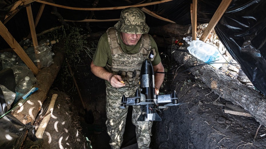 A Ukrainian soldier carries a drone to attack enemy drones.