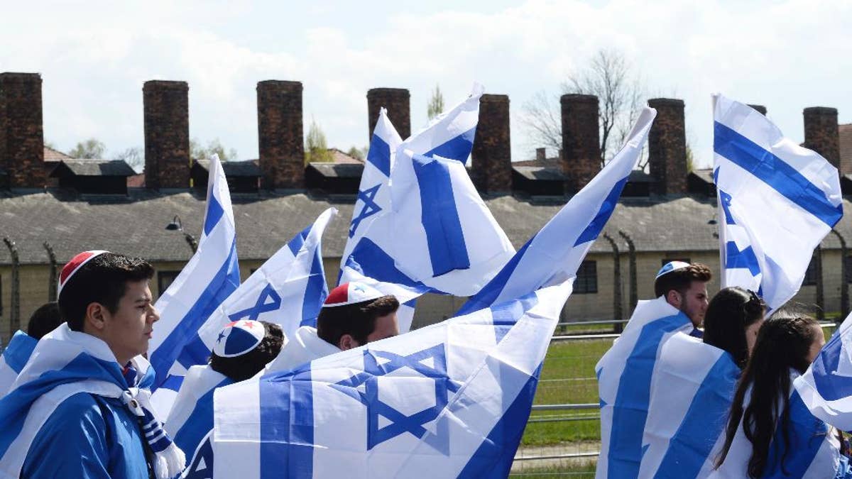 Participants of the yearly March of the Living wave Israeli flags as they walk in the former German Nazi Death Camp Auschwitz-Birkenau, in Oswiecim, Poland, Monday, April 24, 2017. Jews from Israel and around the world marched the 3km route from Auschwitz to Birkenau commemorating the Holocaust victims. (AP Photo/Alik Keplicz)