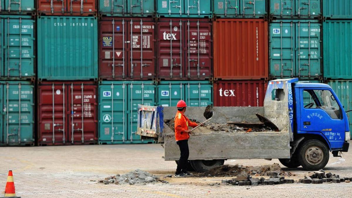 A worker repairs the ground at a container port in Qingdao in eastern China's Shandong province Wednesday, June 8, 2016. China's exports and imports contracted again in May in a sign of weak global and domestic demand. (Chinatopix Via AP) CHINA OUT