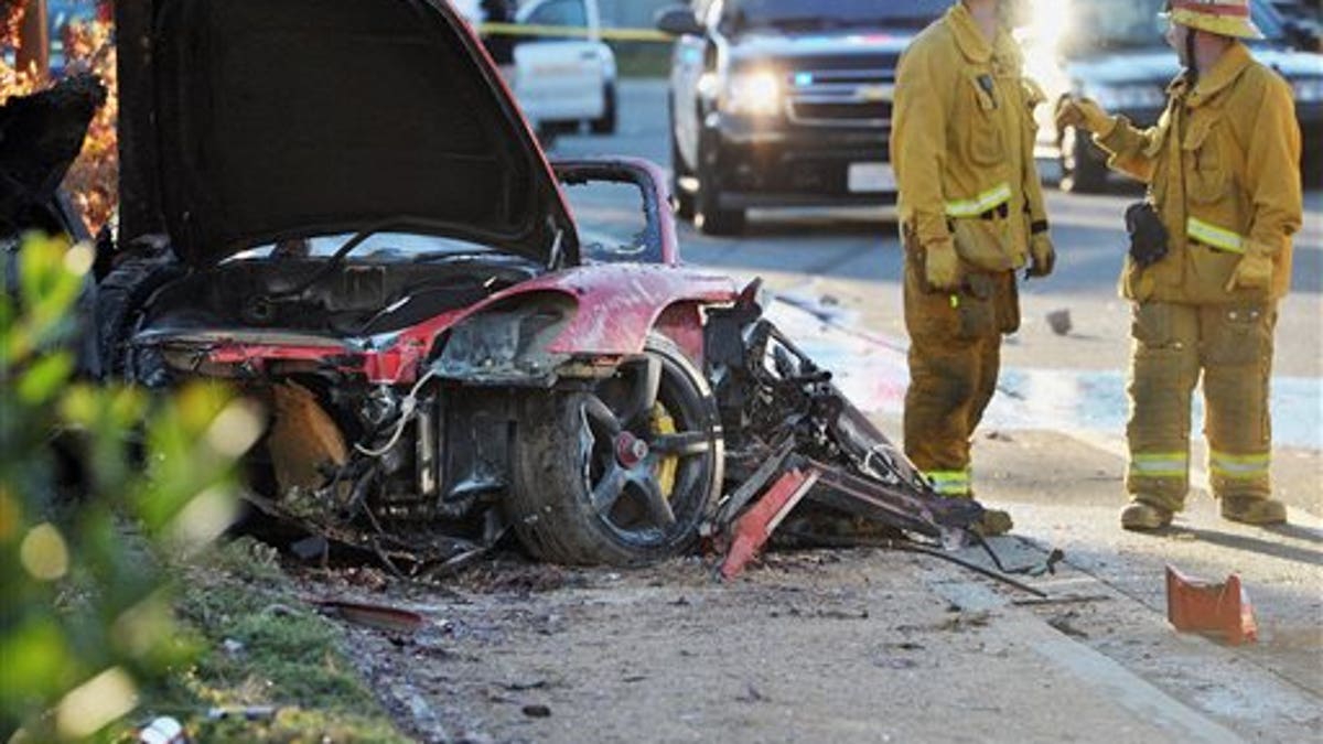 Sheriff's deputies work near the wreckage of a Porsche that crashed into a light pole on Hercules Street near Kelly Johnson Parkway in Valencia, Calif., on Saturday, Nov. 30, 2013. A publicist for actor Paul Walker says the star of the 