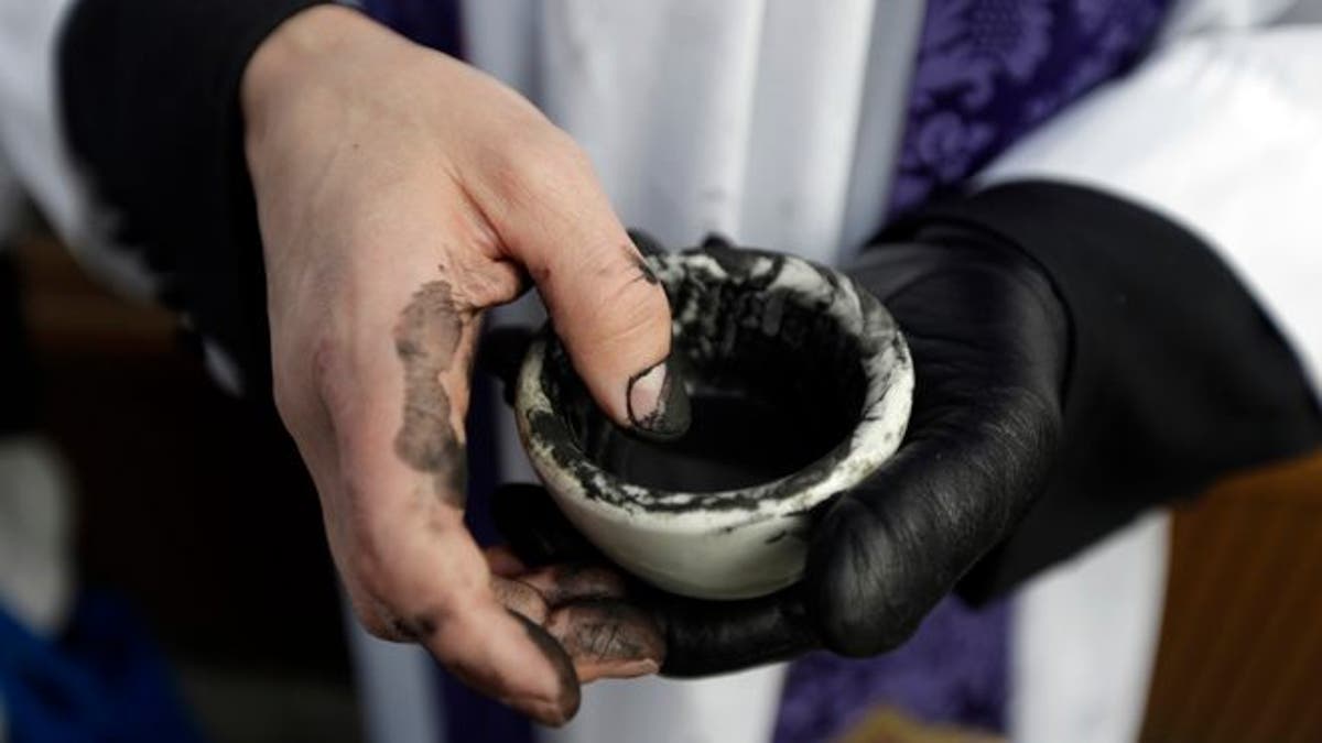 The Rev. Ethan Jewett, with Saint Clement's Episcopal Church, waits to place ash on worshipers' foreheads on Ash Wednesday in front of a Starbucks Coffee at the corner of Chestnut and 19th Streets in Philadelphia on Wednesday, Feb. 13, 2013. Ash Wednesday marks the beginning of Lent, a time when Christians prepare for Easter through acts of penitence and prayer. Jewett said he placed ash on just over 600 worshiper's foreheads. (AP Photo/Matt Rourke)