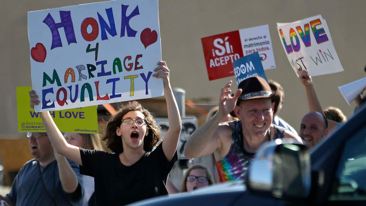 April 28, 2015: Same-sex marriage supporters hold signs encouraging drivers to honk in support of marriage equality during a rally.