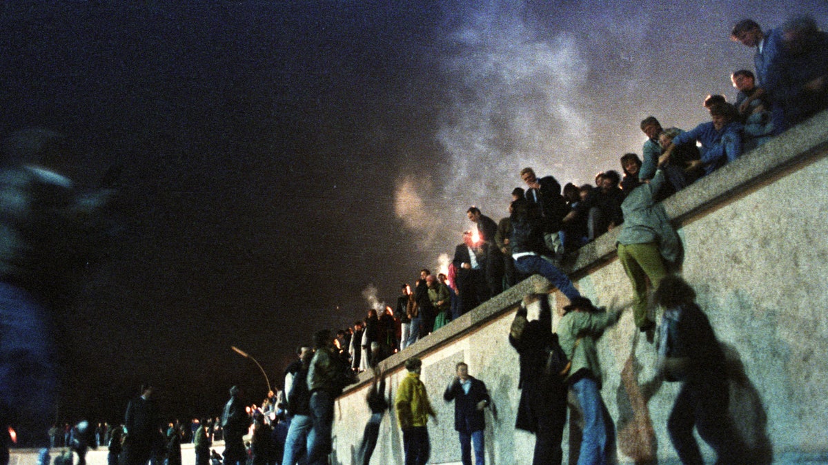 East German citizens climb the Berlin Wall at the Brandenburg Gate after the opening of the border was announced early November 9, 1989. REUTERS/Herbert Knosowski BEST QUALITY AVAILABLE - RTR27VKV