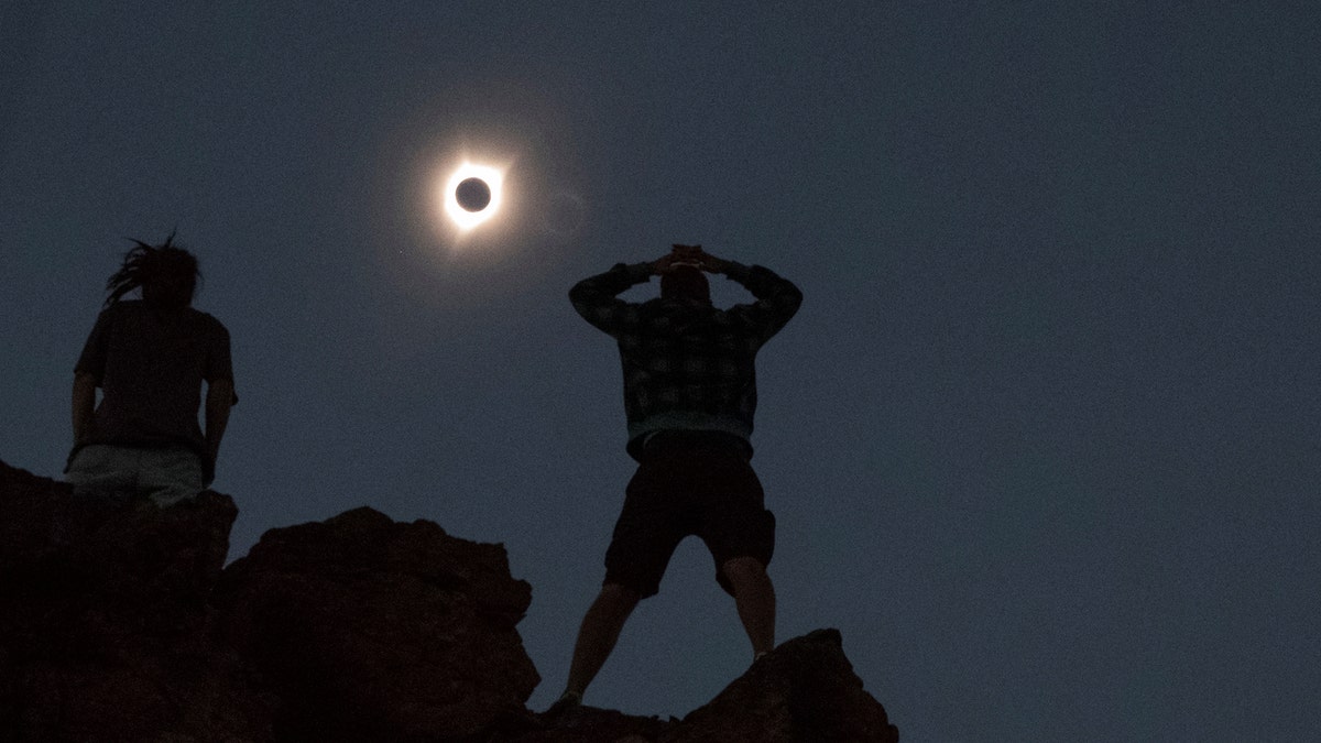 Enthusiasts Tanner Person (R) and Josh Blink, both from Vacaville, California, watch a total solar eclipse while standing atop Carroll Rim Trail at Painted Hills, a unit of the John Day Fossil Beds National Monument, near Mitchell, Oregon, U.S. August 21, 2017. Location coordinates for this image is near 44Â°39'117'' N 120Â°6'042'' W. REUTERS/Adrees Latif - RTS1CPF8