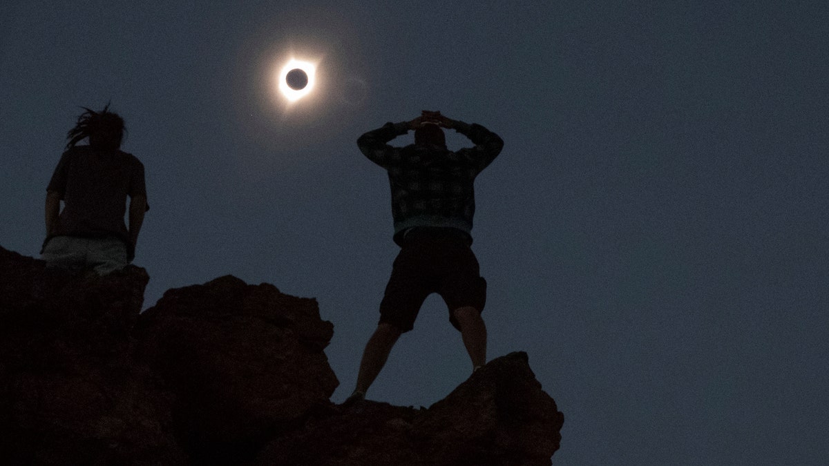 Enthusiasts Tanner Person (R) and Josh Blink, both from Vacaville, California, watch a total solar eclipse while standing atop Carroll Rim Trail at Painted Hills, a unit of the John Day Fossil Beds National Monument, near Mitchell, Oregon, U.S. August 21, 2017. Location coordinates for this image is near 44°39'117'' N 120°6'042'' W. REUTERS/Adrees Latif - RTS1CPF8
