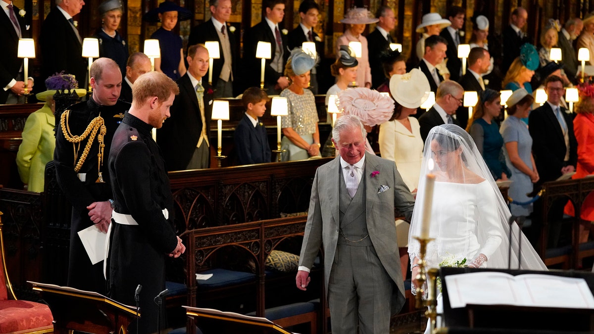 Britain's Prince Harry looks at his bride, Meghan Markle, as she arrives accompanied by the Prince Charles during the wedding ceremony of Prince Harry and Meghan Markle at St. George's Chapel in Windsor Castle in Windsor, near London, England, Saturday, May 19, 2018. (Jonathan Brady/pool photo via AP)