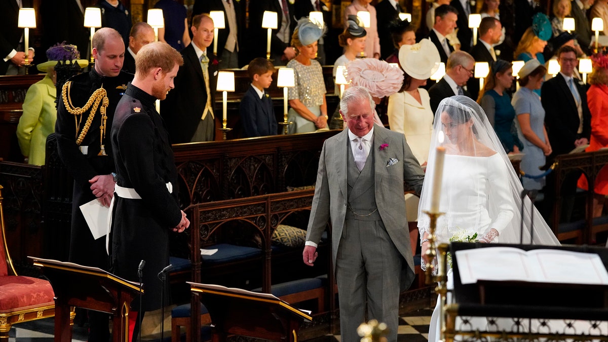 Britain's Prince Harry looks at his bride, Meghan Markle, as she arrives accompanied by the Prince Charles during the wedding ceremony of Prince Harry and Meghan Markle at St. George's Chapel in Windsor Castle in Windsor, near London, England, Saturday, May 19, 2018. (Jonathan Brady/pool photo via AP)