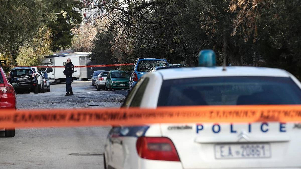 A policeman secures a street where police conducts an investigation at a suburb of Athens, Thursday, Jan. 5, 2017. Greek police say they have recaptured a convicted far-left militant wanted for more than four years after she absconded during her trial on domestic terrorism charges. (AP Photo/Yorgos Karahalis )