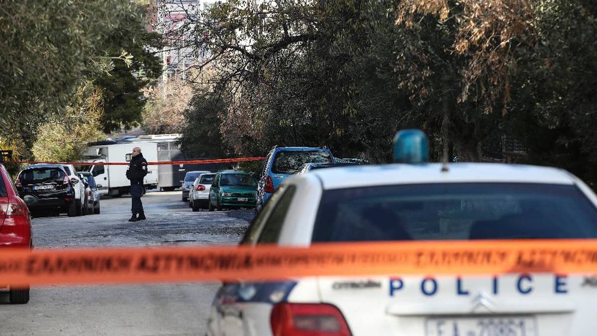 A policeman secures a street where police conducts an investigation at a suburb of Athens, Thursday, Jan. 5, 2017. Greek police say they have recaptured a convicted far-left militant wanted for more than four years after she absconded during her trial on domestic terrorism charges. (AP Photo/Yorgos Karahalis )