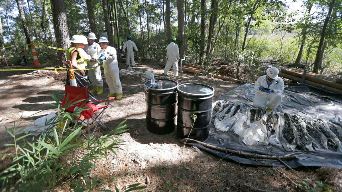In this photo taken Tuesday, Sept. 15, 2015, contractors collect and inspect soil samples taken at a Superfund cleanup site in Navassa, N.C.