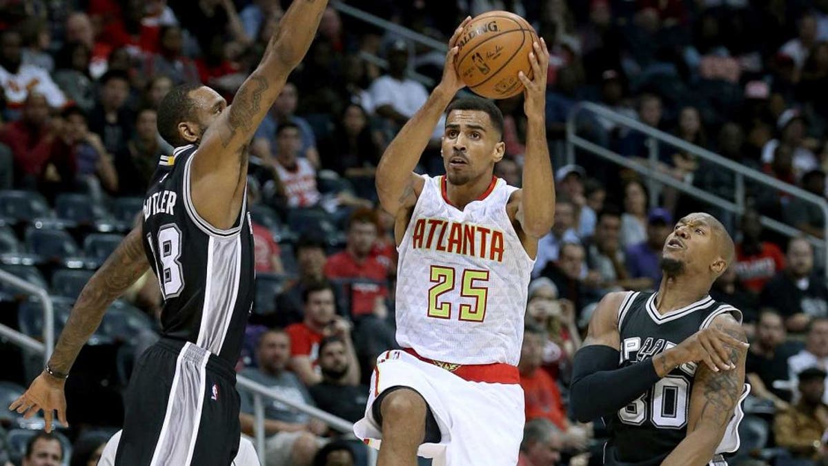 Oct 14, 2015; Atlanta, GA, USA; Atlanta Hawks guard Thabo Sefolosha (25) attempts a shot against San Antonio Spurs forward Rasual Butler (18, left) and forward David West (30) in the first quarter of their game at Philips Arena. Mandatory Credit: Jason Getz-USA TODAY Sports