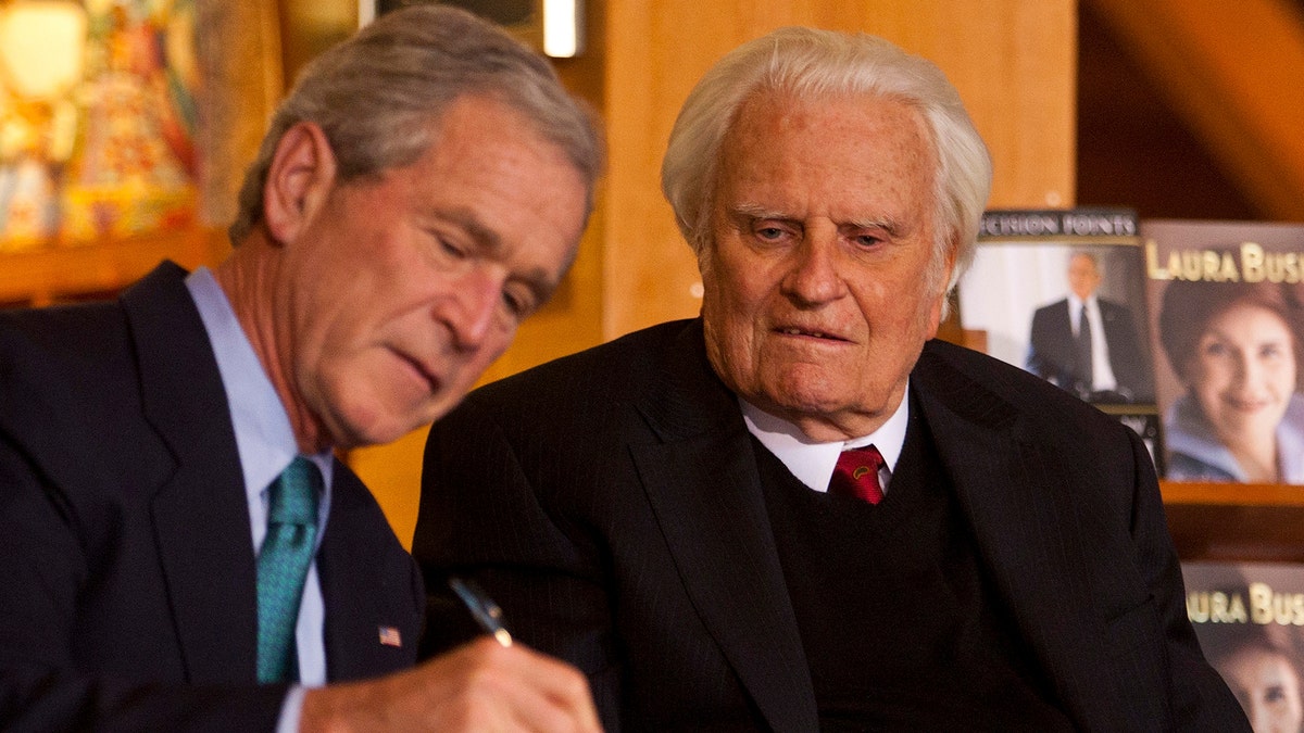 Former U.S. President George W. Bush (L) signs a copy of his new book "Decision Points" for Billy Graham (R) at the Billy Graham Library in Charlotte, North Carolina December 20, 2010. REUTERS/Chris Keane (UNITED STATES - Tags: POLITICS RELIGION) - GM1E6CL09R401
