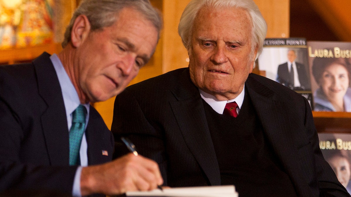 Former U.S. President George W. Bush (L) signs a copy of his new book "Decision Points" for Billy Graham (R) at the Billy Graham Library in Charlotte, North Carolina December 20, 2010. REUTERS/Chris Keane (UNITED STATES - Tags: POLITICS RELIGION) - GM1E6CL09R401