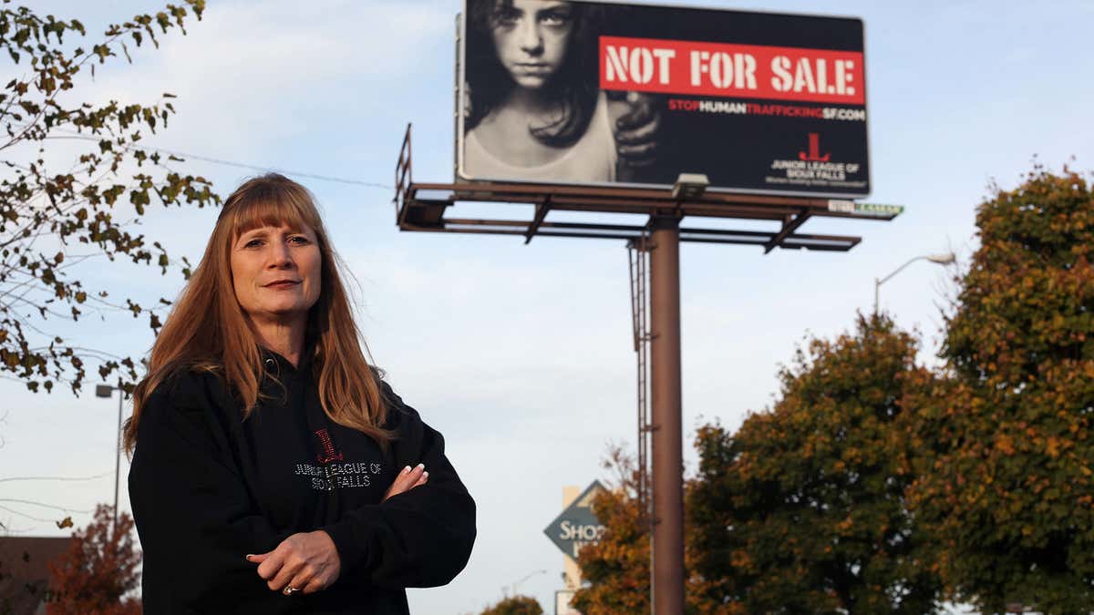 In this Oct. 27, 2015 photo, Dawn Stenberg, from the Junior League of Sioux Falls, stands near the group's anti-human trafficking billboard in Sioux Falls, S.D.