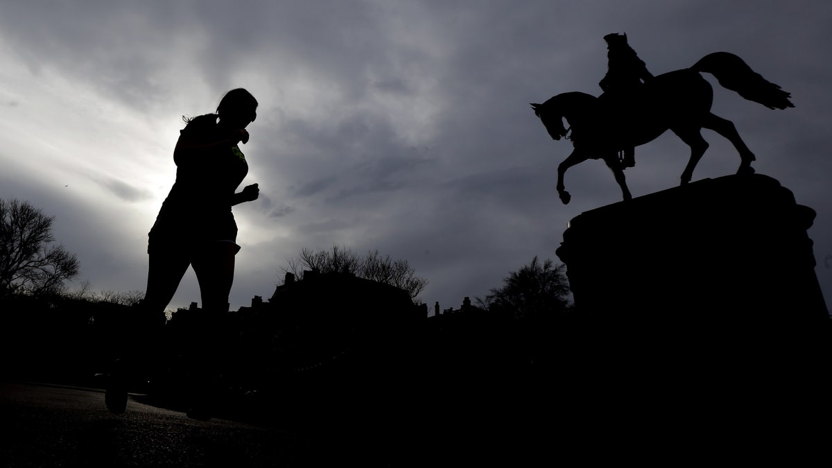 A woman jogs near a statue of George Washington at Boston Common, Tuesday, April 16, 2013, one day after bombs exploded at the finish line of the Boston Marathon. A vigil is expected at Boston Common later in the day to honor the victims of the two bombs that blew up within about 10 seconds and about 100 yards apart Monday near the finish line of the race. (AP Photo/Julio Cortez)