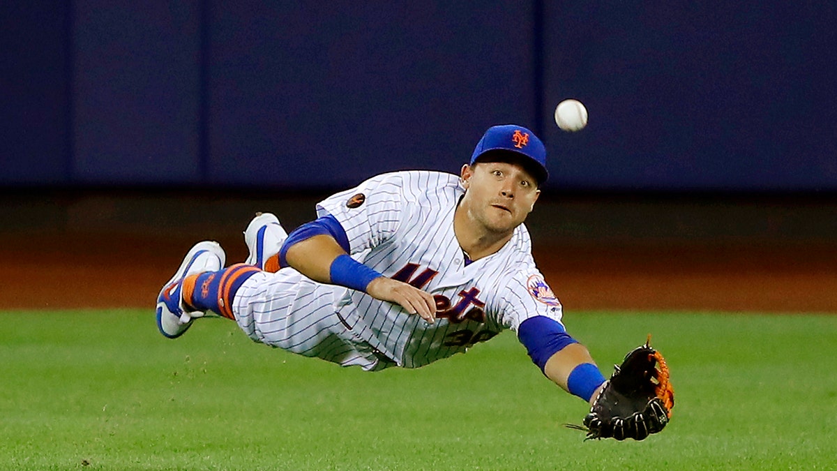 New York Mets center fielder Michael Conforto dives for but can't make the play on a ball hit by Los Angeles Dodgers' Yasiel Puig during the eighth inning of a baseball game Saturday, June 23, 2018, in New York. (AP Photo/Julie Jacobson)