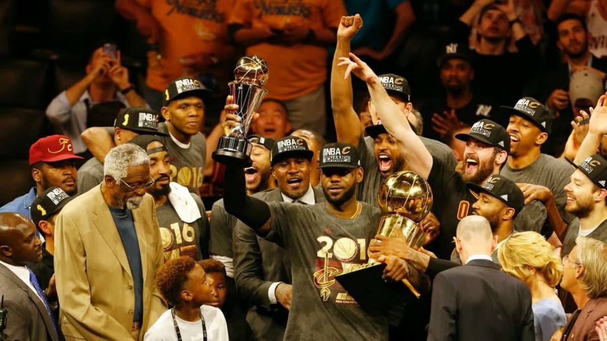 TOPSHOT - Cleveland Cavaliers forward LeBron James hoists the Larry O'Brien and the Finals MVP trophies after defeating the Golden State Warriors to win the NBA Finals on June 19, 2016 in Oakland, California. Powered by an amazing effort from LeBron James, the Cleveland Cavaliers completed the greatest comeback in NBA Finals history, dethroning defending champion Golden State 93-89 to capture their first NBA title. The Cavaliers won the best-of-seven series 4-3 to claim the first league crown in their 46-season history and deliver the first major sports champion to Cleveland since the 1964 NFL Browns, ending the longest such title drought for any American city. / AFP / Beck Diefenbach (Photo credit should read BECK DIEFENBACH/AFP/Getty Images)