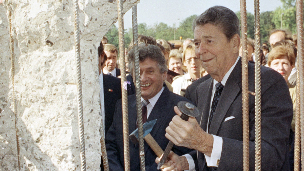 A September 12, 1990 file photo shows former U.S. President Ronald Reagan holding a hammer and chisel next to the Berlin Wall on Poltsdammer Platz in East Berlin. In Berlin in 1987, Reagan challenged Soviet leader Mikhail Gorbachev to 