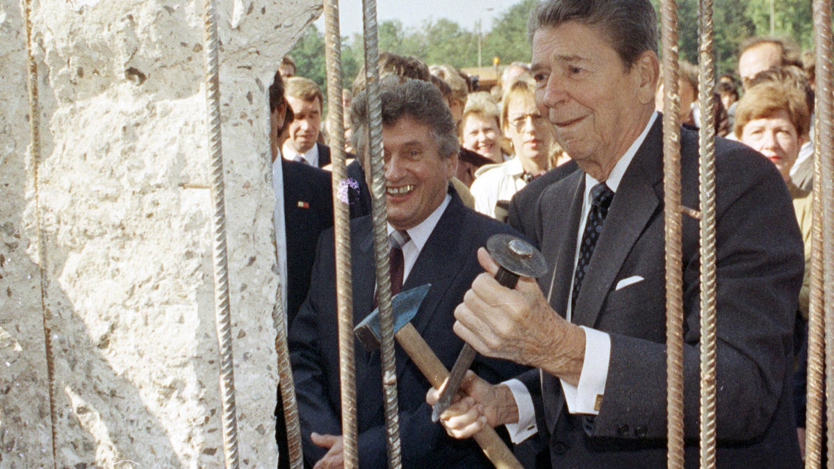 A September 12, 1990 file photo shows former U.S. President Ronald Reagan holding a hammer and chisel next to the Berlin Wall on Poltsdammer Platz in East Berlin. In Berlin in 1987, Reagan challenged Soviet leader Mikhail Gorbachev to 