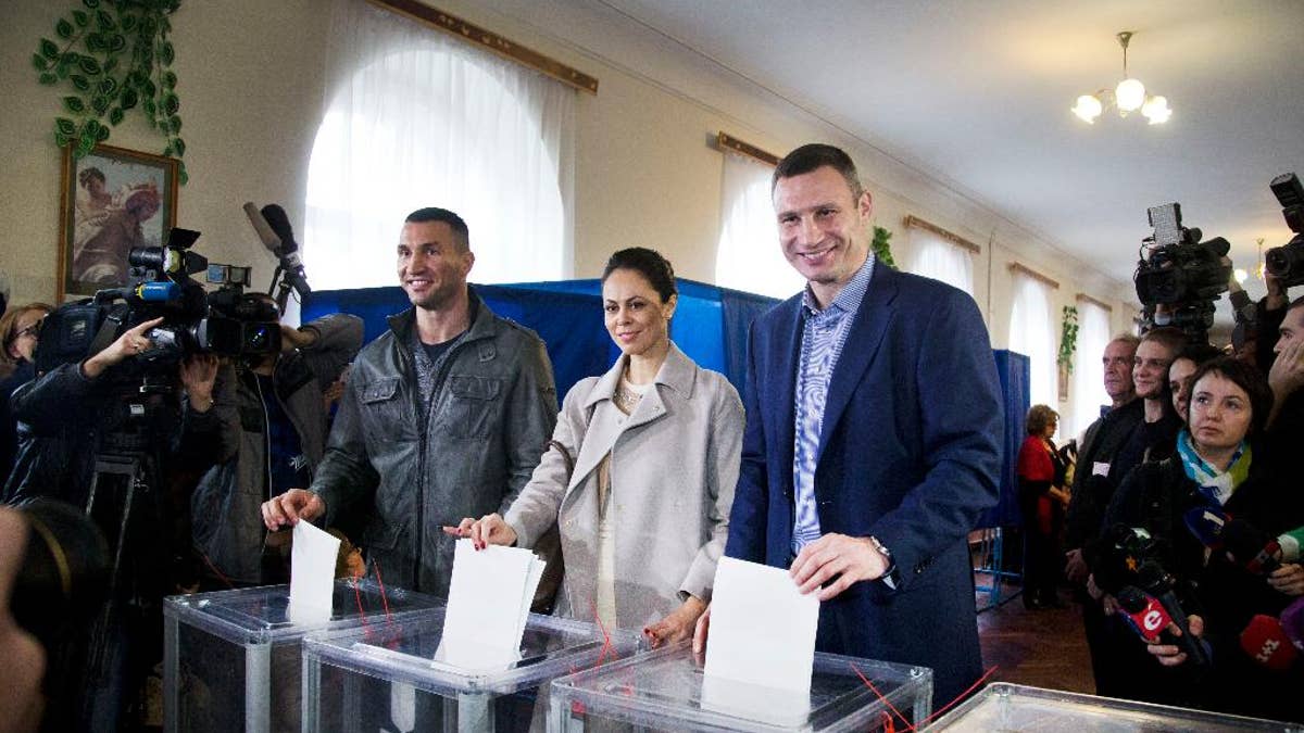 Kiev's current mayor and former heavyweight boxing champion Vitali Klitschko, right, his wife Natalia Klitschko, center, and his brother boxing heavyweight world champion Wladimir Klitschko vote at a polling station in an regional and local elections in Kiev, Ukraine, Sunday, Oct. 25, 2015. Polling stations opened in Ukraine on Sunday for regional and local elections across the country, except for the separatist-held regions in the east. According to local media, Kiev's current mayor and former heavyweight boxing champion Vitali Klitschko is expected to win in the capital. (AP Photo/Efrem Lukatsky)
