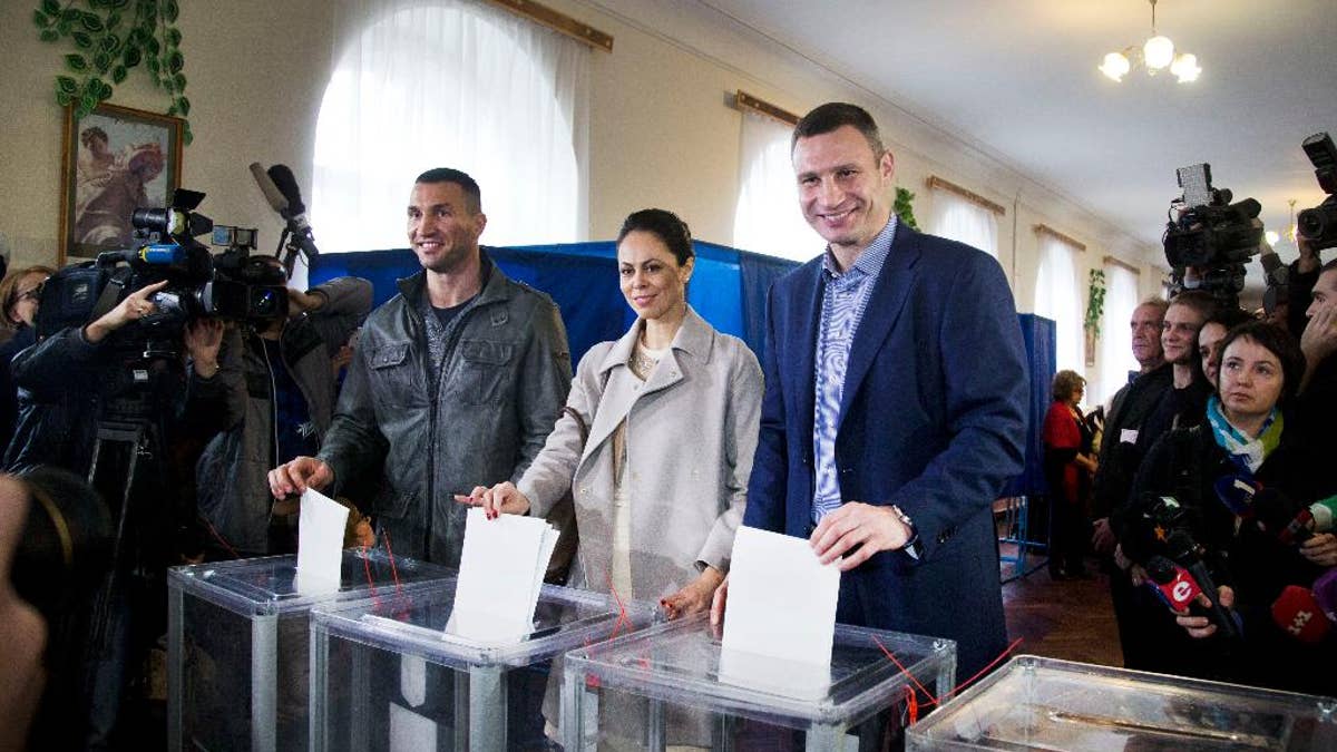 Kiev's current mayor and former heavyweight boxing champion Vitali Klitschko, right, his wife Natalia Klitschko, center, and his brother boxing heavyweight world champion Wladimir Klitschko vote at a polling station in an regional and local elections in Kiev, Ukraine, Sunday, Oct. 25, 2015. Polling stations opened in Ukraine on Sunday for regional and local elections across the country, except for the separatist-held regions in the east. According to local media, Kiev's current mayor and former heavyweight boxing champion Vitali Klitschko is expected to win in the capital. (AP Photo/Efrem Lukatsky)
