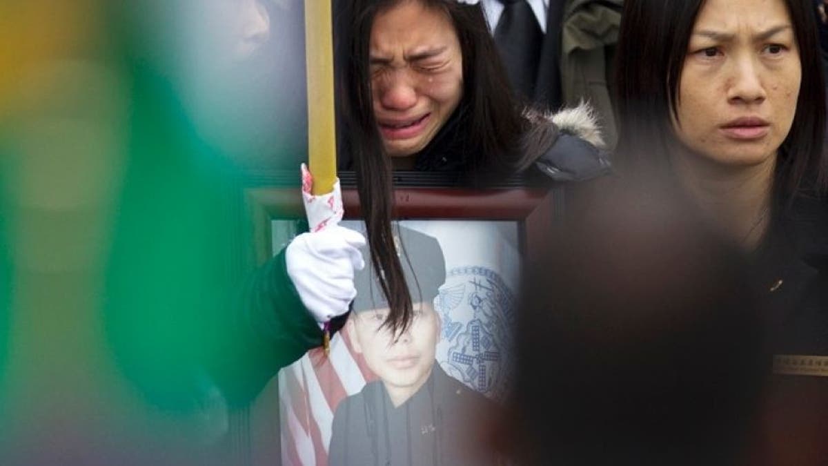 Widow Pei Xia Chen reacts while clutching a photo of slain New York Police Department officer Wenjian Liu as his casket departs his funeral in the Brooklyn borough of New York January 4, 2015. (REUTERS/Carlo Allegri)