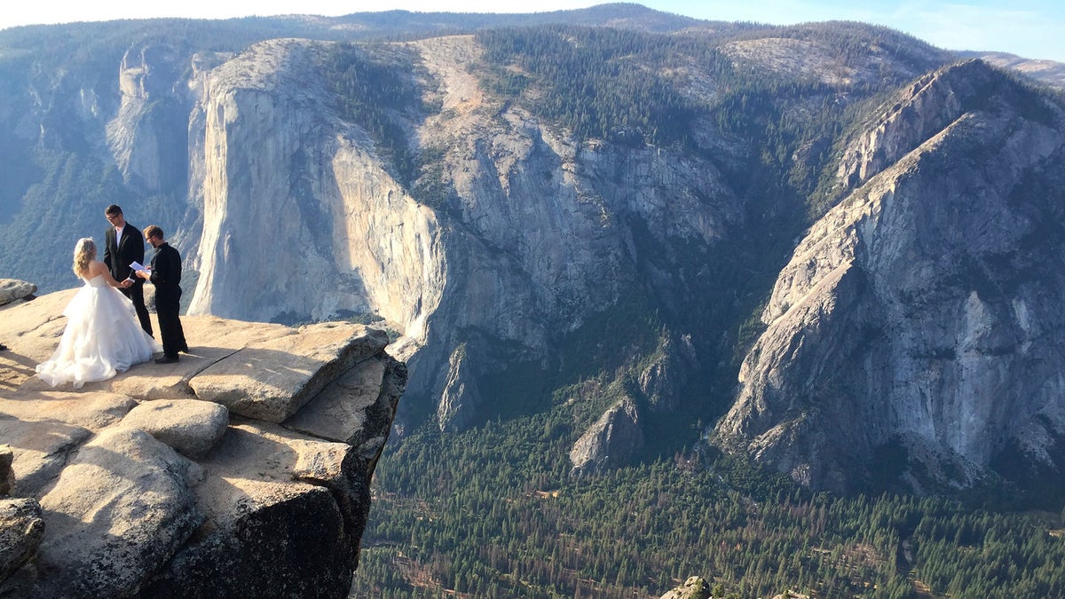 A couple gets married at Taft Point in California's Yosemite National Park on Thursday, Sept. 27, 2018. The viewpoint overlooks Yosemite Valley, including El Capitan, a popular vertical ascent for rock climbers across the globe. (AP Photo/Amanda Lee Myers)