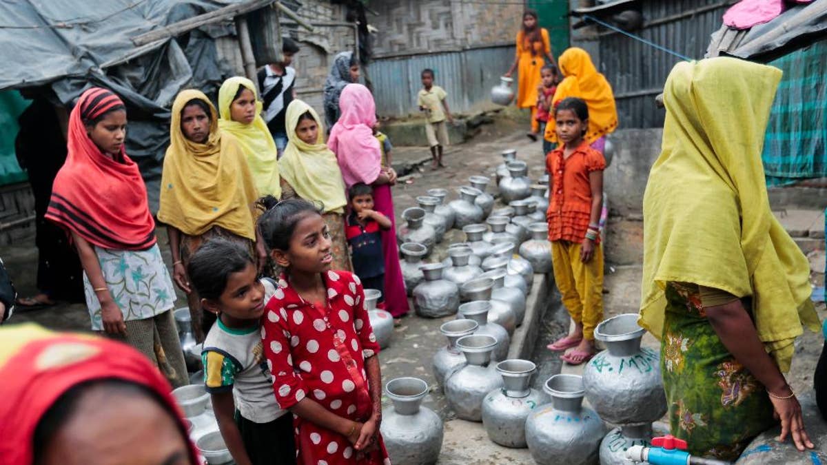 FILE - In this Dec. 3, 2016, file photo, Rohingya women and children wait in a queue to collect water at the Leda camp, an unregistered camp for Rohingya in Teknaf, near Cox's Bazar, a southern coastal district about, 296 kilometers (183 miles) south of Dhaka, Bangladesh. Newly revealed video of Myanmar police beating Rohingya Muslims in northern Rakhine state has weakened months of government claims that its forces have not committed abuses in the region since a deadly insurgent attack in October. The footage has made it more difficult for the government to say at least some abuses are not happening and sown doubts into its dismissals of more grievous allegations. (AP Photo, File)
