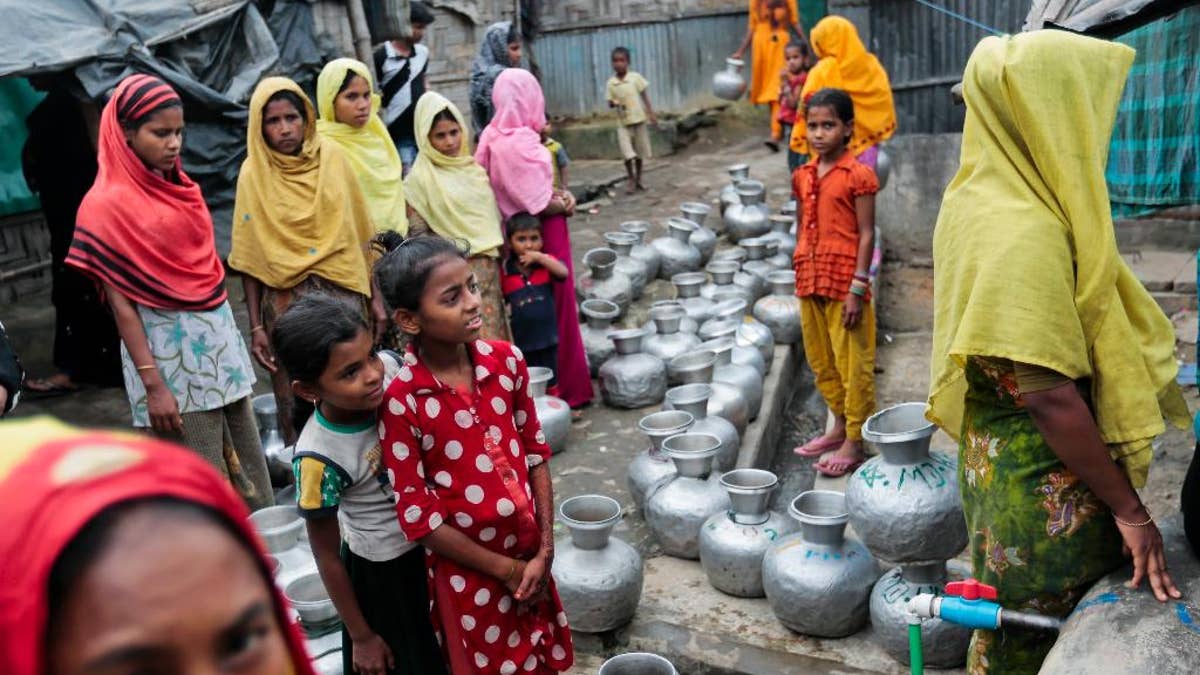 FILE - In this Dec. 3, 2016, file photo, Rohingya women and children wait in a queue to collect water at the Leda camp, an unregistered camp for Rohingya in Teknaf, near Cox's Bazar, a southern coastal district about, 296 kilometers (183 miles) south of Dhaka, Bangladesh. Newly revealed video of Myanmar police beating Rohingya Muslims in northern Rakhine state has weakened months of government claims that its forces have not committed abuses in the region since a deadly insurgent attack in October. The footage has made it more difficult for the government to say at least some abuses are not happening and sown doubts into its dismissals of more grievous allegations. (AP Photo, File)