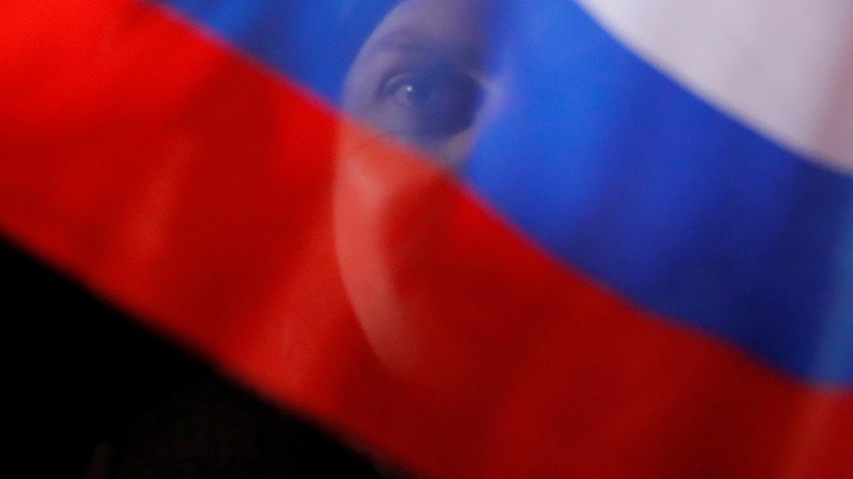 A man waves Russian flag during a rally and concert marking the fourth anniversary of Russia's annexation of the Crimea region, at Manezhnaya Square in central Moscow, Russia March 18, 2018. REUTERS/Maxim Shemetov     TPX IMAGES OF THE DAY - RC179947D6E0