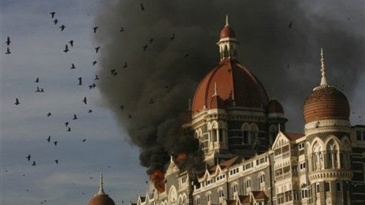 ** FILE ** In this Nov. 27, 2008 file photo, pigeons fly as the Taj Hotel continues to burn during terror attacks in Mumbai, India. Indian Prime Minister Manmohan Singh said Tuesday, Jan. 6, 2009, that he did not believe the November Mumbai attacks gunmen were acting alone, and Pakistani state agencies must have had a hand in the attacks. A ruthless exchange from a transcript of phone calls Indian authorities say they intercepted during the attack were part of a dossier of evidence New Delhi handed Pakistan this week that it says definitively proves that the siege was launched from across the border. (AP Photo/Gautam Singh, File)