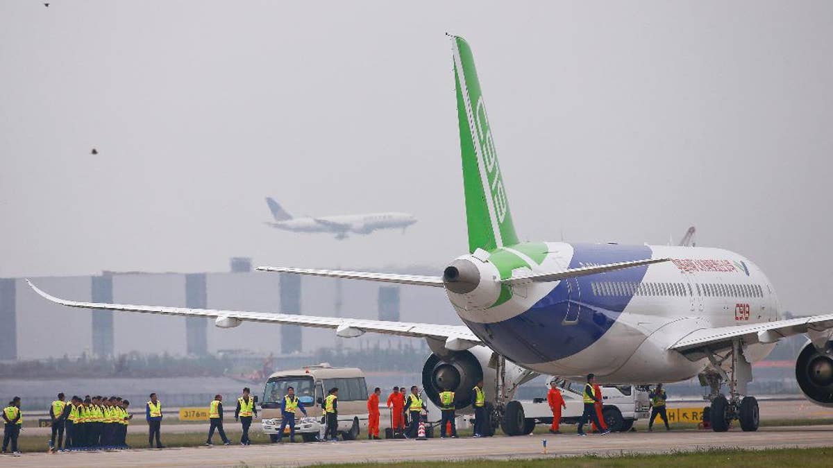 China's home-grown C919 passenger jet is seen at the Shanghai Pudong International Airport ahead of its scheduled maiden flight in Shanghai, China, Friday, May 5, 2017. China is touting the C919 as a rival to single-aisle jets the Airbus A320 and Boeing 737. The plane was originally due to fly in 2014 before being delivered to buyers in 2016, but has been beset by delays blamed on manufacturing problems. (Aly Song/Pool Photo via AP)