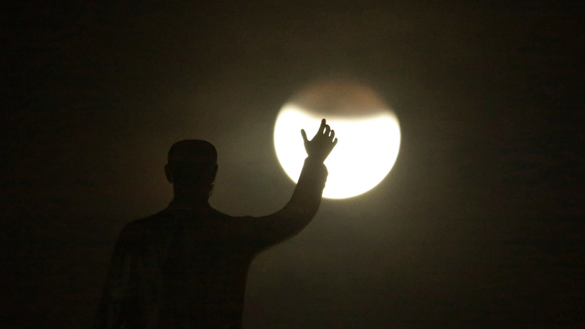 A blood moon rises in front of the statue of the founder of the federal capital, President Juscelino Kubitschek, during a complete lunar eclipse in Brasilia, Brazil, Friday, July 27, 2018. Skywatchers around much of the world are looking forward to a complete lunar eclipse that will be the longest this century. (AP Photo/Eraldo Peres)