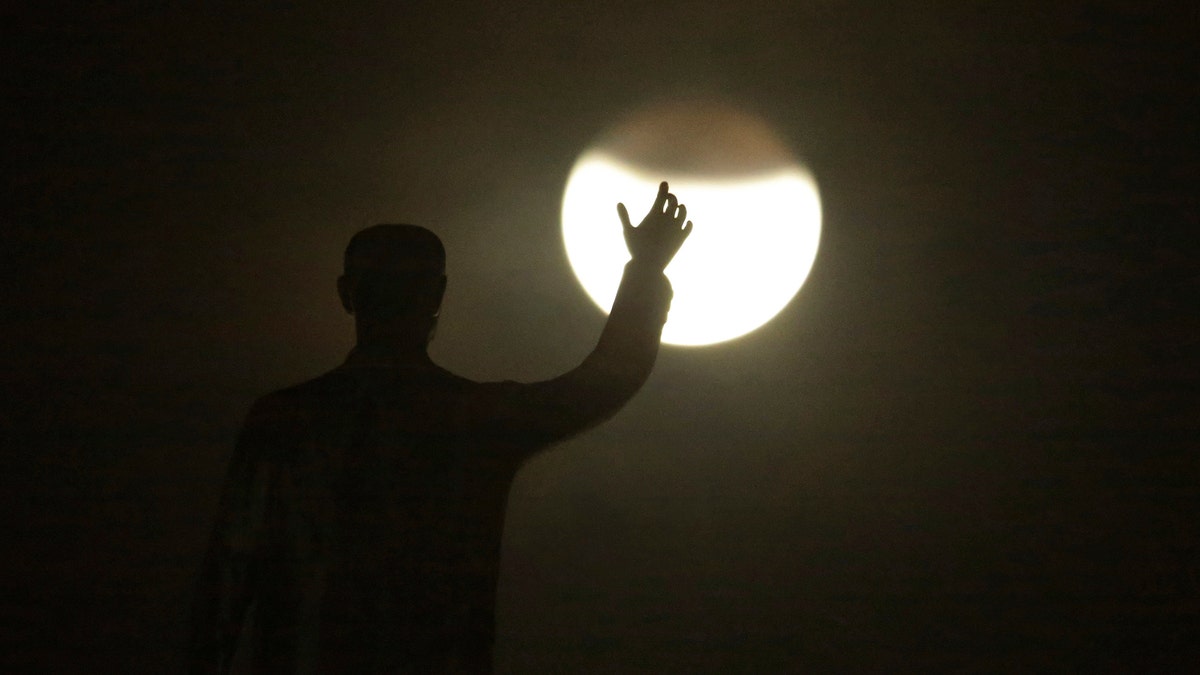 A blood moon rises in front of the statue of the founder of the federal capital, President Juscelino Kubitschek, during a complete lunar eclipse in Brasilia, Brazil, Friday, July 27, 2018. Skywatchers around much of the world are looking forward to a complete lunar eclipse that will be the longest this century. (AP Photo/Eraldo Peres)