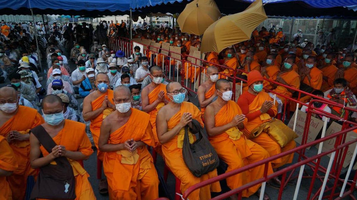 Buddhist monks of the Dhammakaya sect sit anticipating police raid outside the Dhammakaya sect temple in Pathum Thani, north of Bangkok, Thailand, Sunday, February 19, 2017. Police in Thailand who spent three days searching the vast Buddhist temple for a prominent monk accused of financial wrongdoing have kept up the pressure, sending fresh forces to confront devotees and monks at the compound's gates. (AP Photo/Dake Kang)
