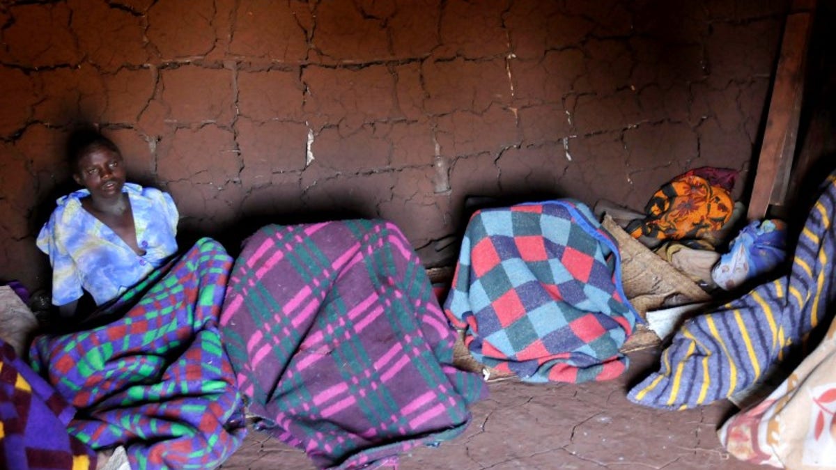 A teenager from Uganda's Sebei tribe sits inside a mud hut after undergoing female genital mutilation in Bukwa district
