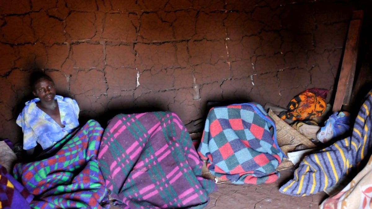 A teenager from Uganda's Sebei tribe sits inside a mud hut after undergoing female genital mutilation in Bukwa district