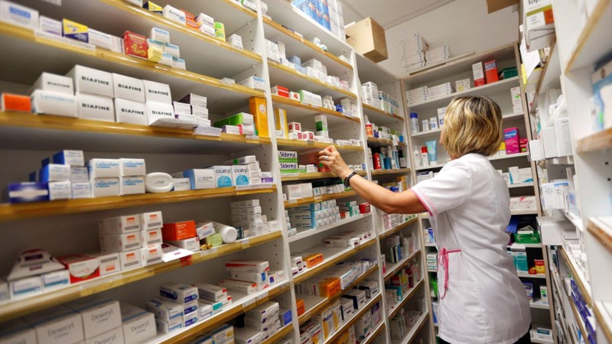 A pharmacist selects drugs inside her pharmacy in Bordeaux