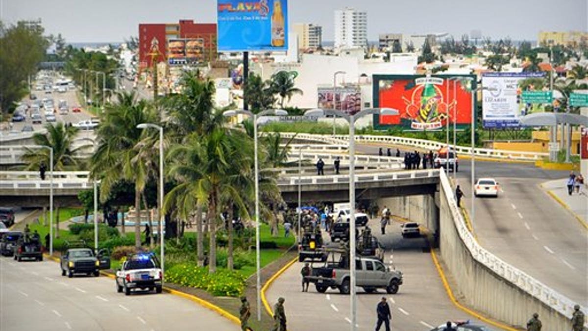 In this Tuesday Sept. 20, 2011 file photo, soldiers and police block off an area where 35 bodies lie under an overpass in Veracruz, Mexico. Masked gunmen blocked traffic on the busy avenue in a Gulf of Mexico coastal city and left the bodies piled in two trucks and on the ground, according to authorities. The scene was a sharp escalation in drug violence in Veracruz state, which sits on an important route for drugs and Central American migrants heading north. Five years after President Felipe Calderon launched an offensive against Mexico's five main drug cartels, the nation is now dominated by two powerful organizations that appear poised for a one-on-one battle to control drug markets and trafficking routes. (AP Photo)