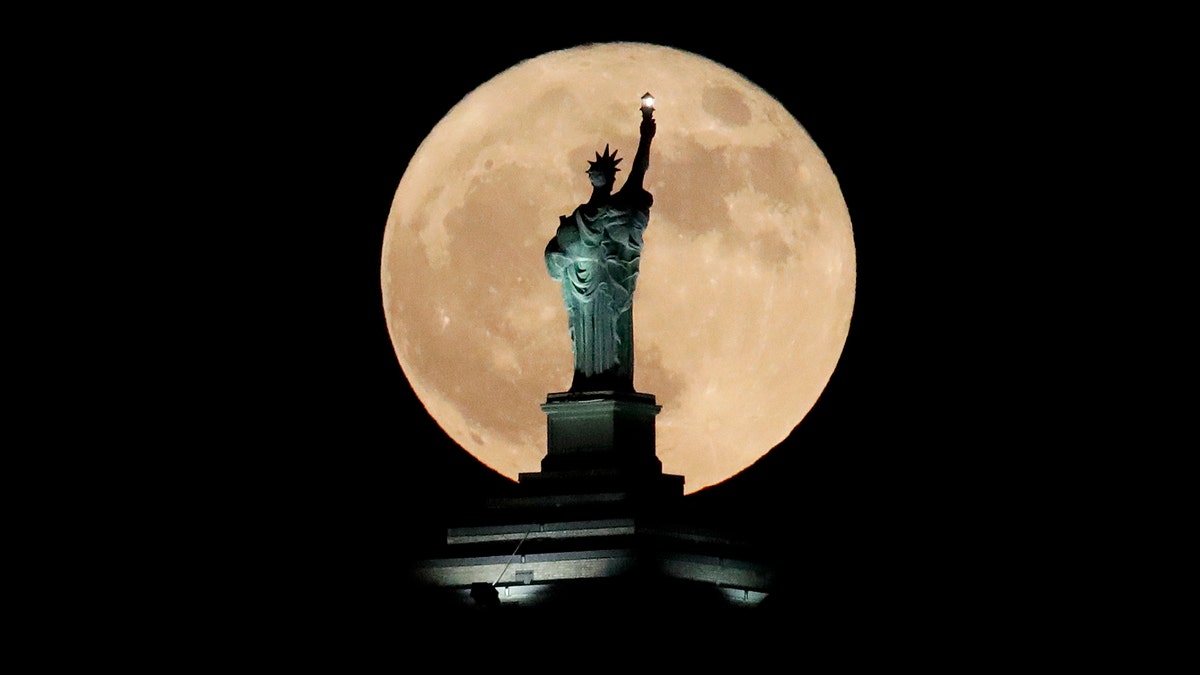 A supermoon rises in front of a replica of the Statue of Liberty sitting atop the Liberty Building in downtown Buffalo, N.Y., Sunday, Dec. 3, 2017. December's full moon appears bigger and brighter in the sky as it sits closer than average to Earth. Sunday's moon is the first of three consecutive supermoons. The next two will occur on Jan. 1, 2018, and Jan. 31. (AP Photo/Julio Cortez)