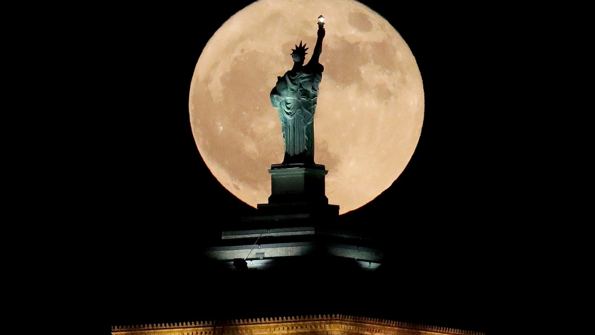 A supermoon rises in front of a replica of the Statue of Liberty sitting atop the Liberty Building in downtown Buffalo, N.Y., Sunday, Dec. 3, 2017. December's full moon appears bigger and brighter in the sky as it sits closer than average to Earth. Sunday's moon is the first of three consecutive supermoons. The next two will occur on Jan. 1, 2018, and Jan. 31. (AP Photo/Julio Cortez)