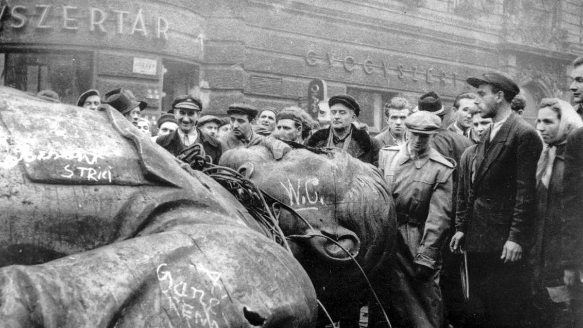 FILE - In this Oct. 24, 1956 file photo, people gather around a fallen statue of Soviet leader Josef Stalin in front of the National Theater in Budapest, Hungary. The uprising in Hungary began on Oct. 23, 1956 with demonstrations against the Stalinist regime in Budapest and was crushed eleven days later by Soviet tanks amid bitter fighting. For Hungary, a pro-Russian leader in the White House offers hope the Western world might end the sanctions imposed over Russia’s annexation of Crimea and its role in eastern Ukraine. Many Poles, instead, fear a U.S-Russian rapprochement under Trump could threaten their own security interests. To most Poles, NATO represents the best guarantee for an enduring independent state in a difficult geographical neighborhood. (AP Photo/Arpad Hazafi, file)