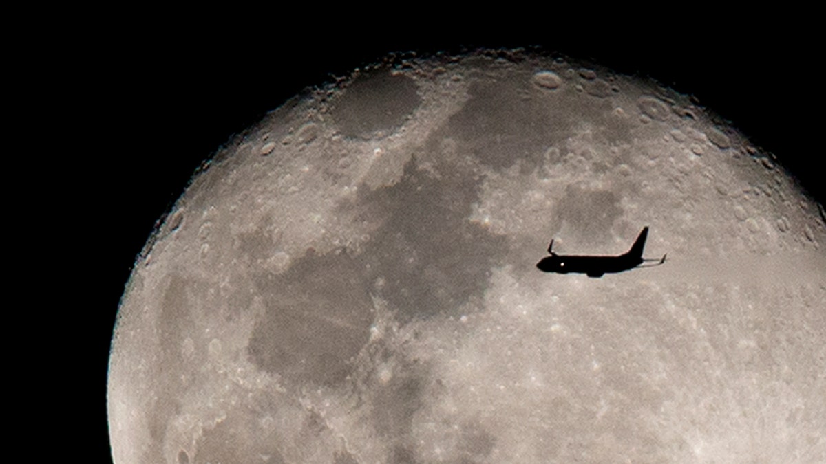 An airplane flies against the backdrop of the rising moon after taking off from Miami International airport, Sunday, Feb. 12, 2017, above Surfside, Fla. (AP Photo/Wilfredo Lee)
