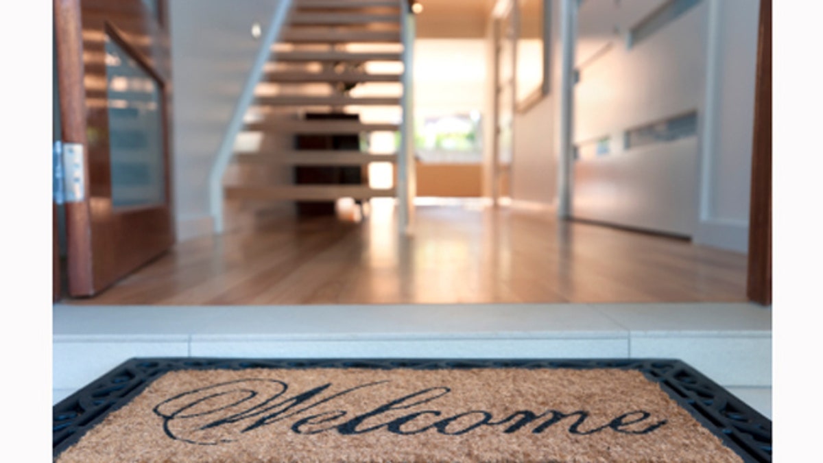 2c41e0bb-Close up of a welcome mat in front of an inviting house