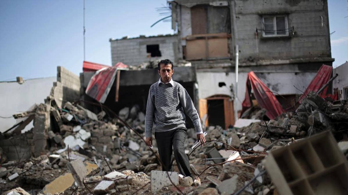 In this Monday, Nov. 17, 2014 photo, Mahmoud Abu Amer, 37, walks amid the ruins of an apartment building where 16 relatives were killed by an Israeli airstrike on July 29, in Khan Younis, Gaza. The building was one of scores targeted by Israel in its war last summer with the Islamic militant Hamas. Israel says it only attacked homes used by militants for military purposes, while Palestinians say warplanes often struck without regard for civilians. (AP Photo/Adel Hana)