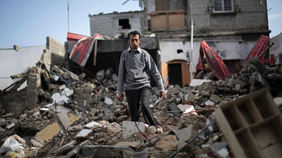 In this Monday, Nov. 17, 2014 photo, Mahmoud Abu Amer, 37, walks amid the ruins of an apartment building where 16 relatives were killed by an Israeli airstrike on July 29, in Khan Younis, Gaza. The building was one of scores targeted by Israel in its war last summer with the Islamic militant Hamas. Israel says it only attacked homes used by militants for military purposes, while Palestinians say warplanes often struck without regard for civilians. (AP Photo/Adel Hana)