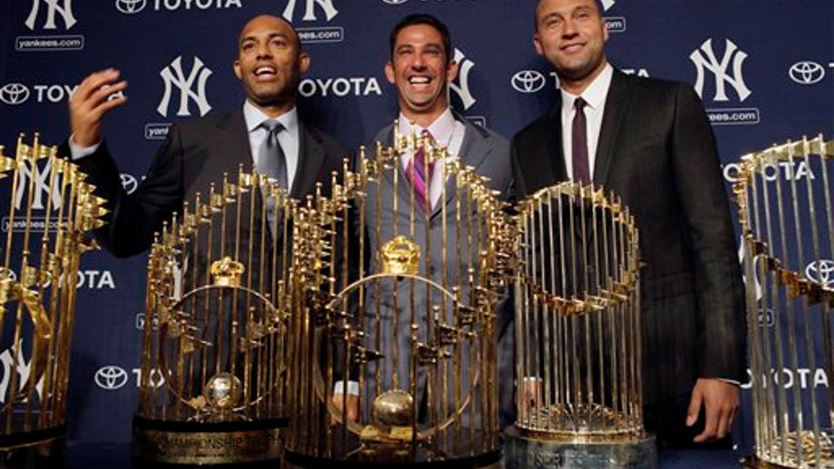 New York Yankees baseball player Jorge Posada, center, is flanked by teammates Mariano Rivera, left, and Derek Jeter, while standing behind five World Series trophies during a news conference to announce his retirement at Yankee Stadium in New York, Tuesday, Jan. 24, 2012. (AP Photo/Seth Wenig)